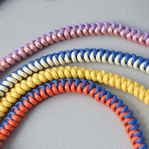 Close-up of multicolored braided rope bag chains with spiral woven texture detail