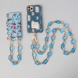 Close-up of blue acrylic and gold metal chain strap with stylish denim phone cases