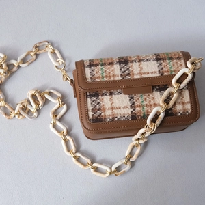 Detail of checkered shoulder bag with marble texture acrylic chain strap and gold hardware