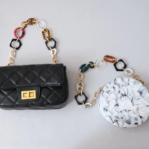 Close-up of colorful acrylic resin chain straps on black quilted and marble bags