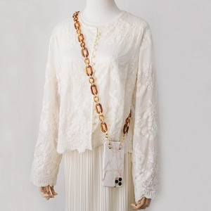 Detail view of amber resin chunky chain strap on a white marble phone case with gold hooks
