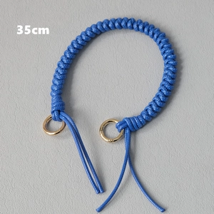 Detail of 35cm blue braided rope bag handle strap with polished gold circular clasps
