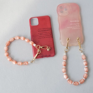 Detail of pink cat-eye stone beads and gold metal clasps on a stylish phone strap