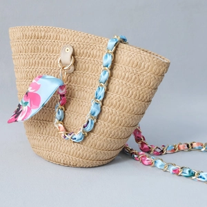 Detail of hand-woven straw bucket bag featuring gold chain and floral scarf strap
