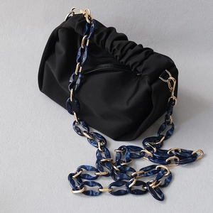 Close-up of black pouch bag with marble resin and gold metal chunky chain strap