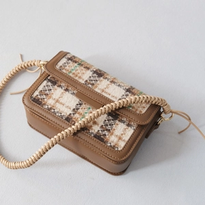 Close-up of retro plaid crossbody bag with woven rope strap and gold hardware details
