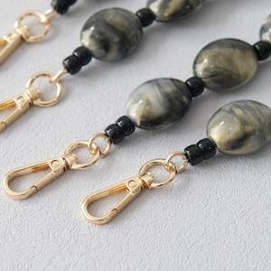 Detail of acrylic marble bead chain strap with golden lobster clasp for bags and phones