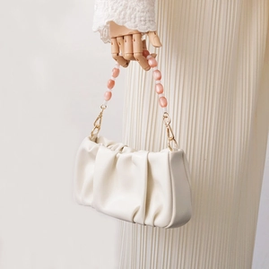 Detail of white pleated cloud bag with pink and white beaded handle and gold metal clasp