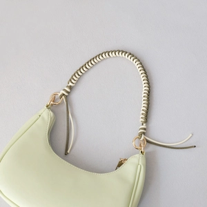 Detail of mint green crescent bag featuring a dual-tone woven rope handle and gold hardware