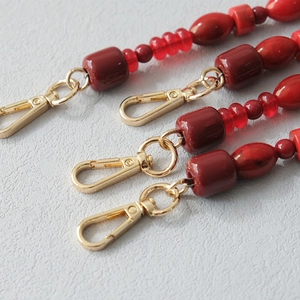 Detail of red acrylic beads in various shapes with premium gold-toned metal clasps