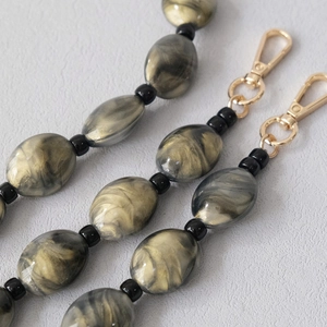 Detail of marble pattern acrylic bead chain with polished gold lobster clasps