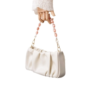 White ruched cloud bag with pink translucent resin beaded chain strap on model hand