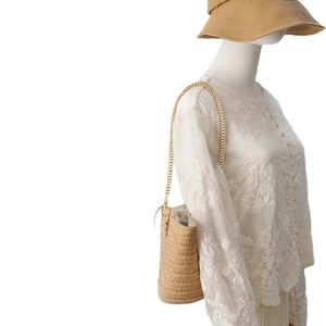 Beige straw woven bucket bag with spiral texture and matching braided shoulder strap