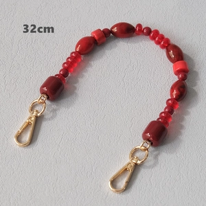 Detail view of 32cm red acrylic beaded bag strap with golden lobster clasps and marble beads