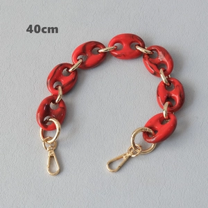 Détail d'une bandoulière chaîne acrylique rouge marbré 40cm avec fermoirs dorés