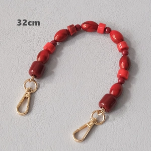 Detail of red acrylic beaded strap with marble pattern beads and gold lobster clasps
