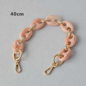 Détail de la bandoulière de 40cm en acrylique rose marbré avec fermoirs dorés