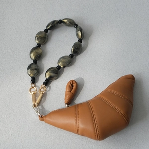 Detailed view of a brown pleated croissant bag with marble acrylic bead handle