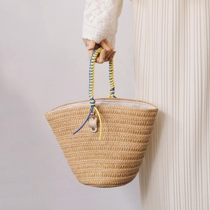 Detail of woven straw basket bag with vibrant yellow and blue rope handle detail