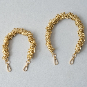 Détail de bandoulières en chaîne métallique dorée avec fermoirs mousquetons pour sacs