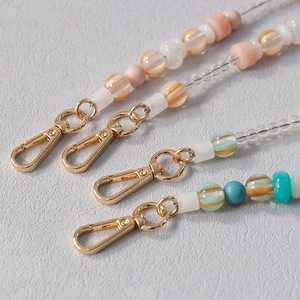 Detail of colorful acrylic bead chains with golden lobster clasps and striped resin beads