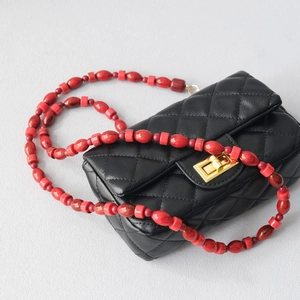 Quilted black bag with distinctive bright red acrylic bead shoulder strap and gold clasp