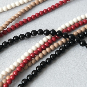 Détail macro de chaînes en perles acryliques brillantes en noir, rouge, blanc et abricot