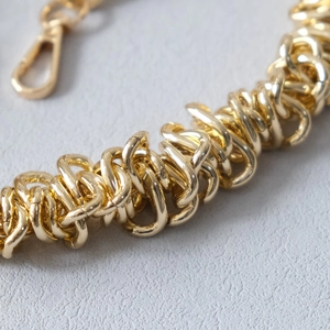 Détail d'une bandoulière chaîne en métal doré épais avec texture lisse et mousqueton