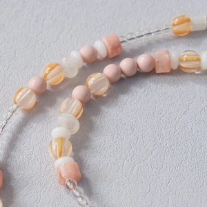 Close-up of mixed acrylic beads featuring peach pink and cream white pearls and striped charms