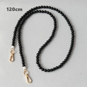 Détail d'une bandoulière en perles acryliques noires de 120 cm avec fermoirs dorés
