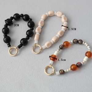 Three acrylic beaded phone chains with spring buckles in black, beige, and amber colors