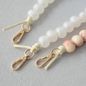 Macro detail of acrylic bead strap with golden lobster clasp and marbled textures