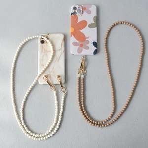 Détail de lanières en perles acryliques crème et marron avec crochets dorés pour mobiles