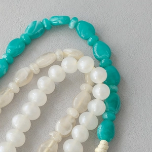 Close-up of turquoise marble and pearl acrylic beads with a woven cord detail
