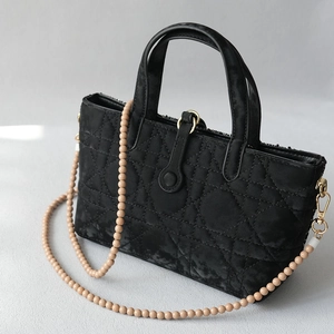 Sac à main noir matelassé avec couture classique et longue bandoulière en perles contrastées