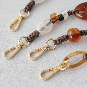 Close-up of acrylic bead straps with gold lobster clasps and braided knots for bags