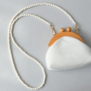 Détail d'un sac bandoulière vintage en cuir blanc avec cadre en bois et longue bandoulière