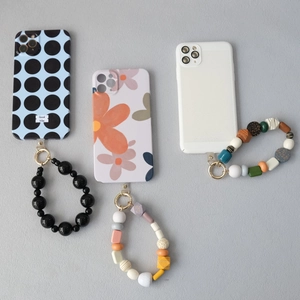 Three assorted acrylic beaded phone charms with patterned stylish cases on grey texture