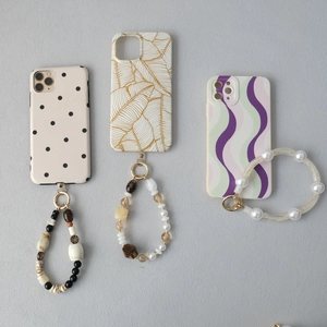 Close-up of beaded phone straps with resin pearls and vintage patterned phone cases