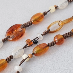 Macro view of amber and cream acrylic beads with intricate woven cord craftmanship