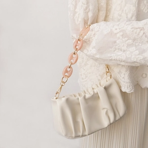 Détail de la bandoulière en résine rose et métal doré sur un sac à main crème