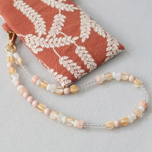 Detail of beaded mobile strap with pink and orange acrylic beads and golden clasp