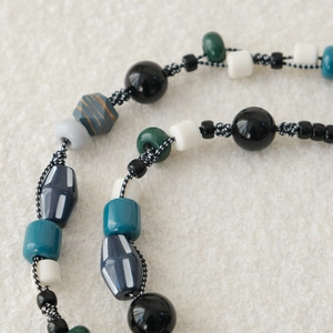 Gros plan détaillé d'une chaîne en perles acryliques montrant le tressage artisanal fin