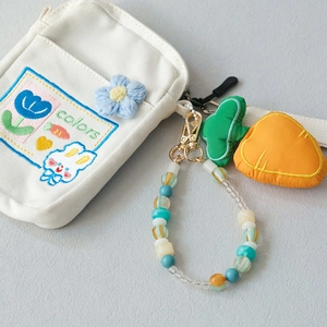 Close-up of white canvas bag with colorful rabbit embroidery and acrylic beaded strap