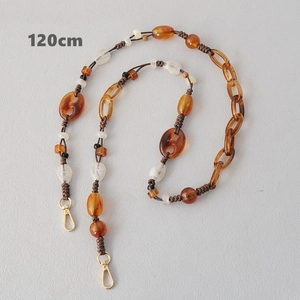 Detail view of 120cm amber acrylic bead strap with golden lobster clasps and braided rope