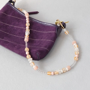 Detail view of colorful acrylic beads and glass charms on a stylish crossbody bag strap