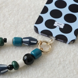 Close-up of colorful acrylic beaded strap connected to a blue polka dot phone case