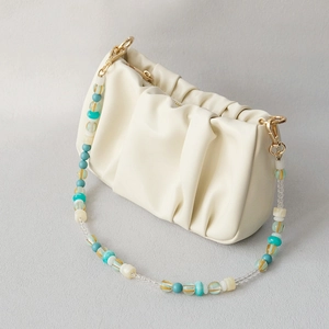 Detail of off-white ruched dumpling bag with colorful acrylic beaded strap and gold hooks
