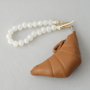 Detail of brown leather croissant mini pouch with white beaded handle and gold clip