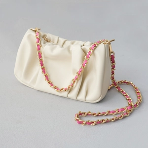 Detail view of cream white pleated cloud bag with pink and gold woven chain strap